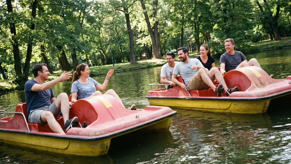 Bootsverleih Decksteiner Weiher – Kollegen paddeln auf mehreren Tretbooten über den Weiher