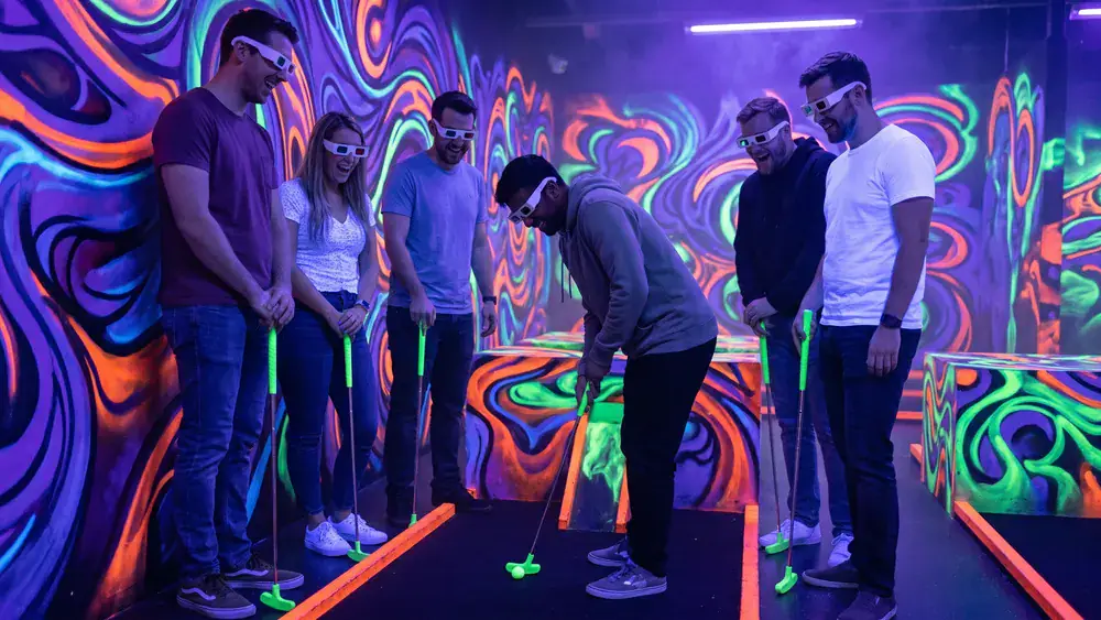 Schwarzlicht Minigolf in Köln – Kollegen spielen mit 3D-Brillen Minigolf in leuchtender Neonwelt