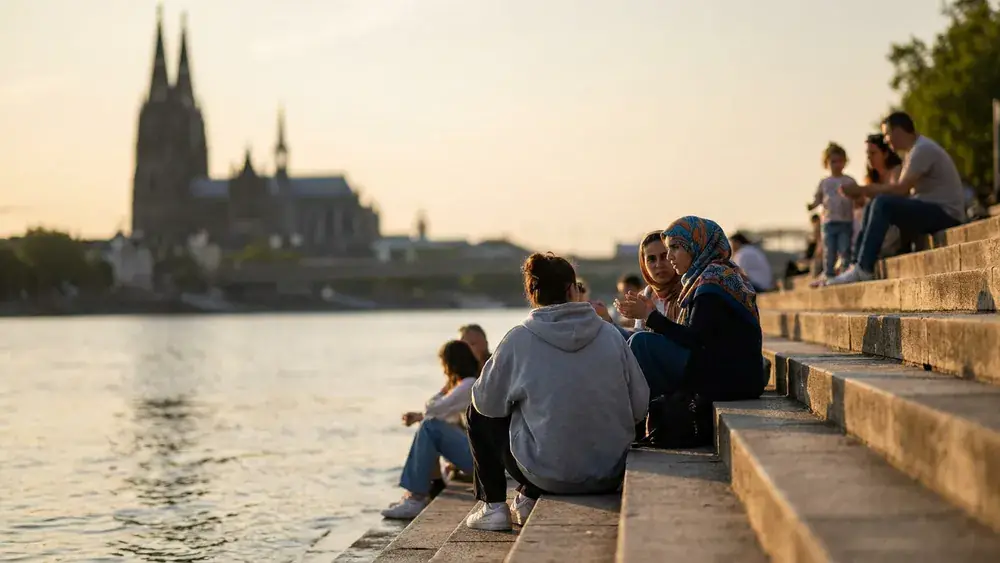 Rheinboulevard Deutz in Köln – Menschen sitzen auf der Freitreppe am Rhein mit Blick auf den Dom