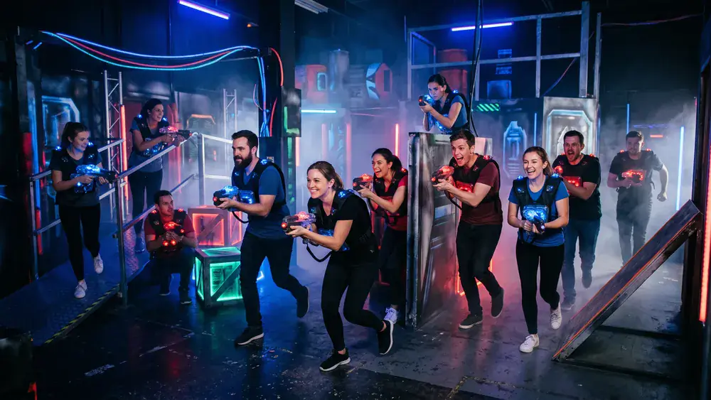 Lasertag in Köln – Kollegen mit Sensorwesten spielen in einer dunklen Neon-Arena