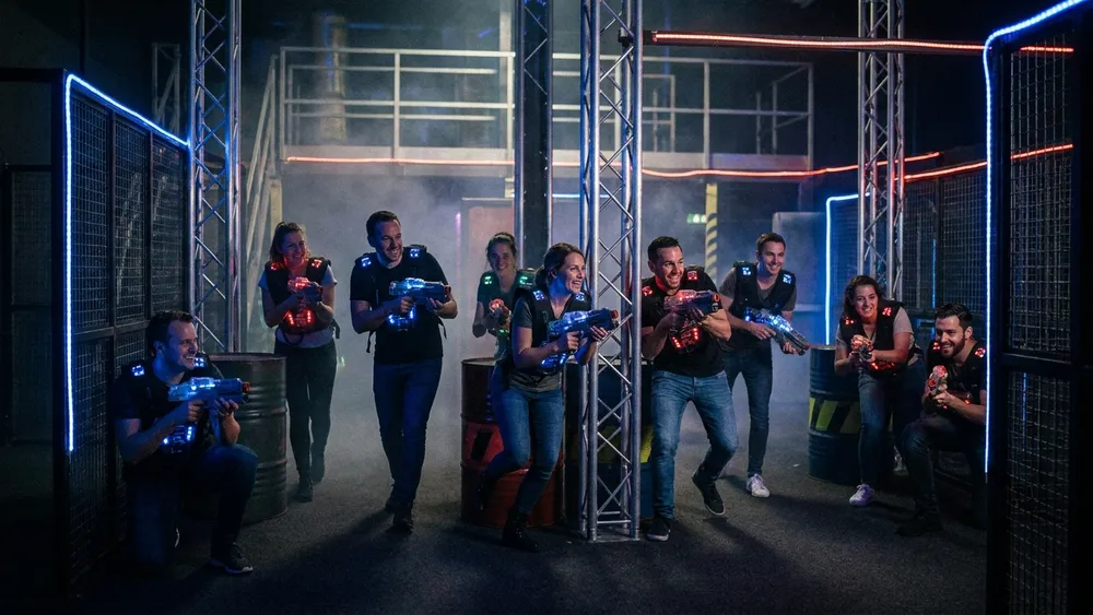 Lasertag in Stuttgart - Erwachsene in Sensorwesten spielen mit Phasern in einer dunklen Neon-Arena