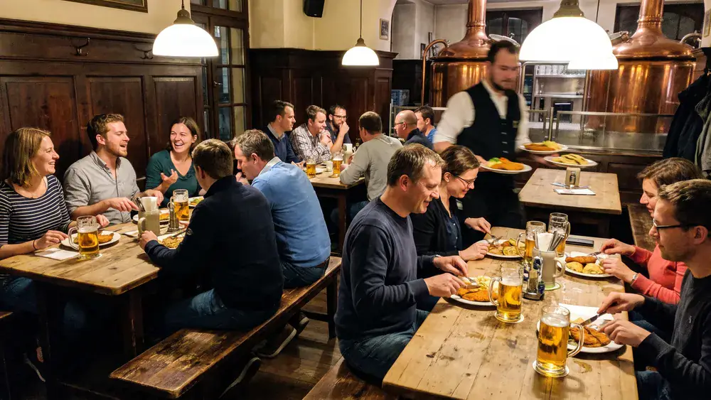 Brauhaus in Stuttgart – Kollegen trinken Hellbier an langen Tischen mit schwäbischen Spezialitäten