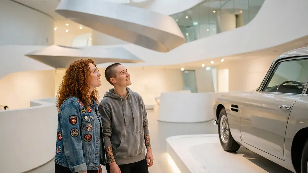 Porsche Museum in Stuttgart – Zwei Personen betrachten Sportwagen in futuristischer Museumsarchitektur