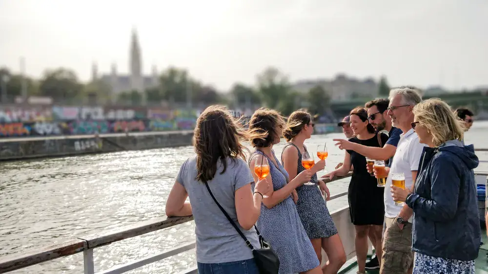 DDSG Donaurundfahrt in Wien – Kollegen stehen an Deck eines Donauschiffs mit Blick auf die Uferpromenade