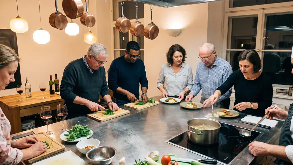 Kochkurs in Wien – Kollegen kochen gemeinsam ein 3-Gänge-Menü an einer großen Kochinsel