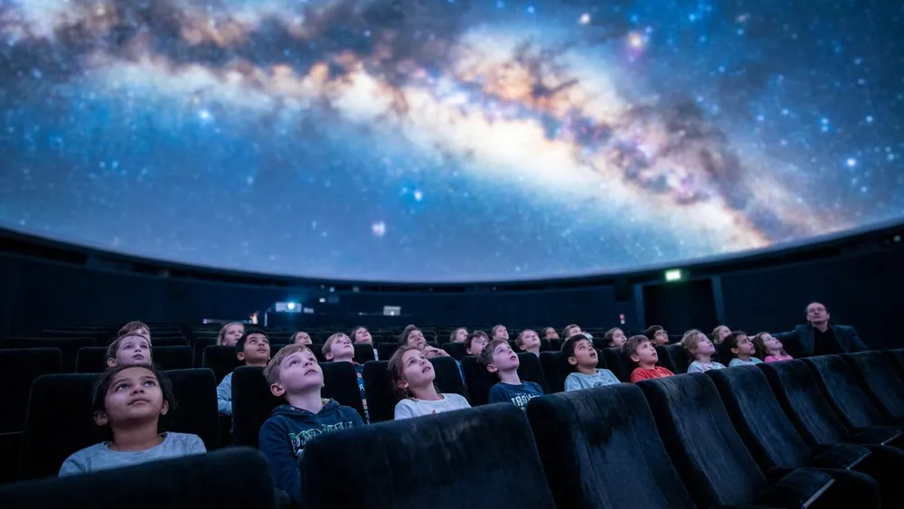 Planetarium Wien – Schulklasse blickt in den Kuppelhimmel mit Sternenprojektion