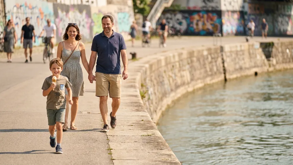 Donaukanal Wien – Familie spaziert die Kanalpromenade entlang vor Graffiti-Wänden