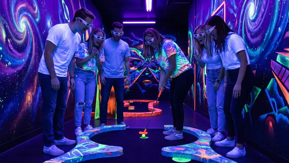Schwarzlicht Minigolf in Wien – Kollegen spielen mit 3D-Brillen Minigolf in leuchtender Neonwelt bei der Weihnachtsfeier