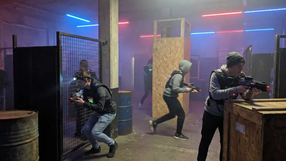 LaserTag Würzburg – Kollegen in taktischen Westen spielen in einer dunklen Neon-Arena am Hauptbahnhof