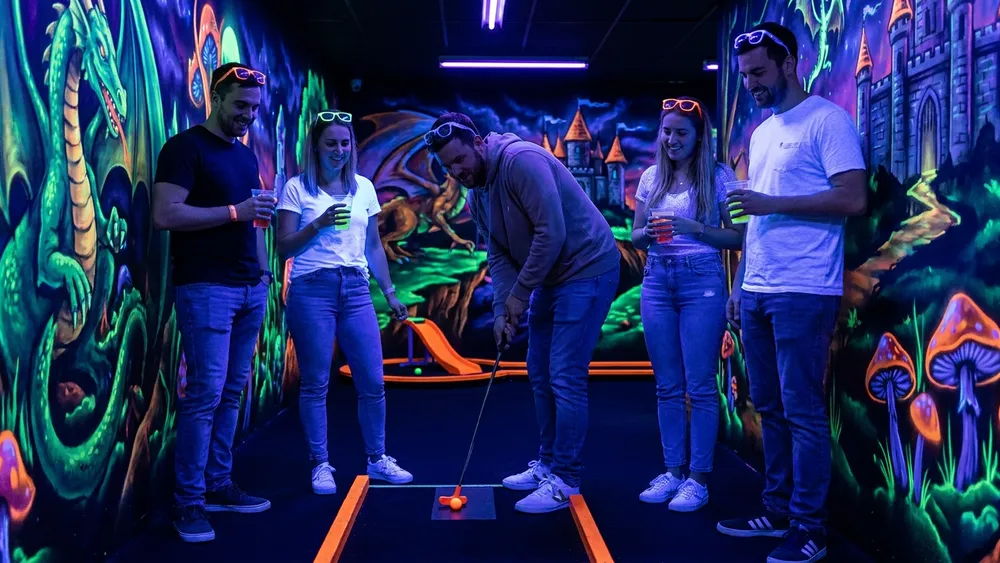 Schwarzlicht Minigolf in Würzburg - Erwachsene spielen 3D-Minigolf unter UV-Licht mit Drinks