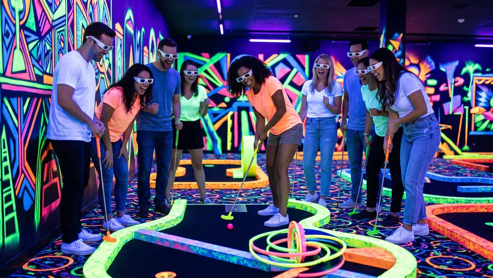 Schwarzlichtfabrik Würzburg – Kollegen spielen mit 3D-Brillen Minigolf unter Schwarzlicht